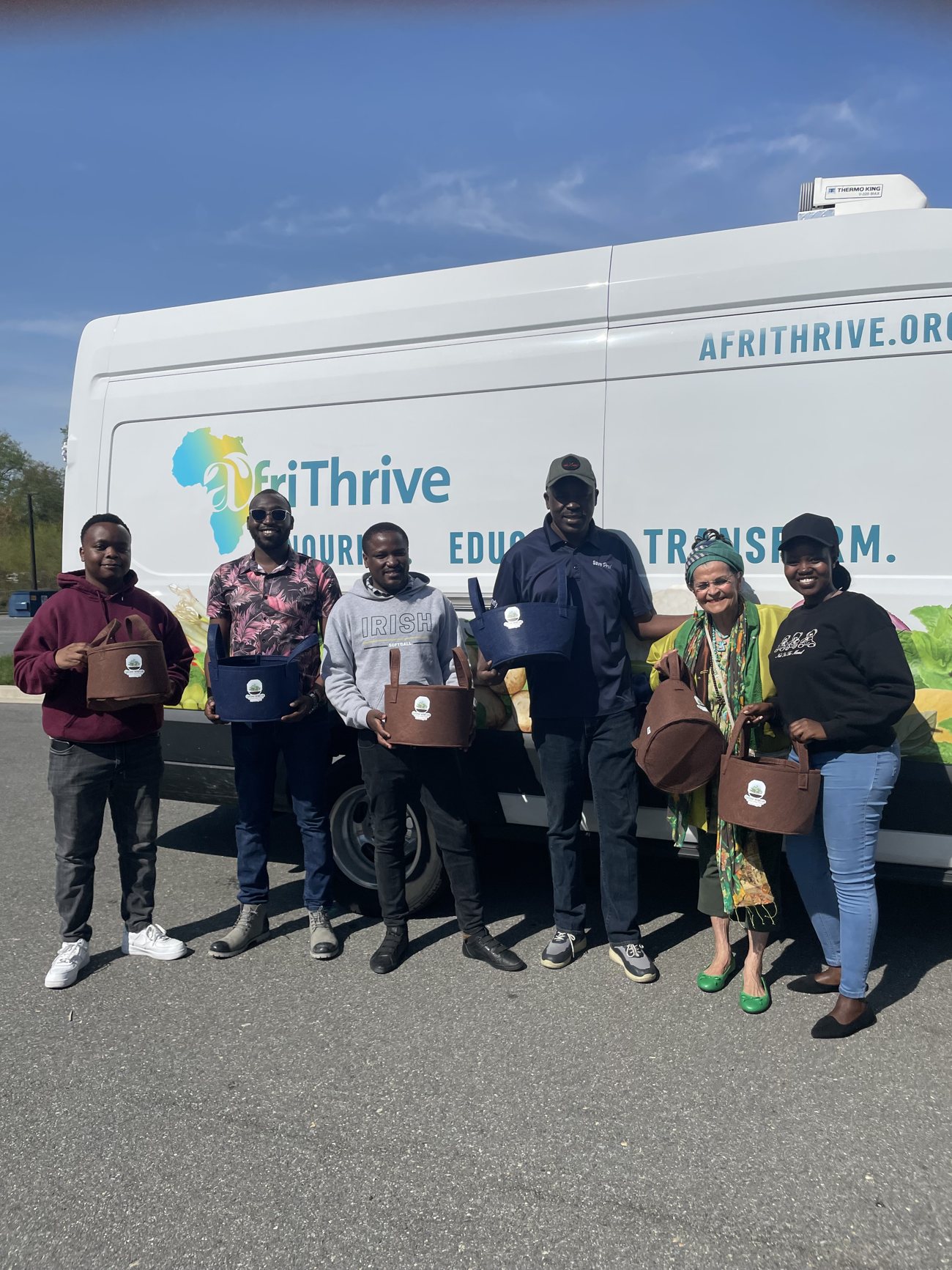 AfriThrive team members holding grow bags in front of a branded van