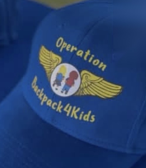 A blue BackPack4Kids cap with golden wings and the words Operation Backpack4Kids