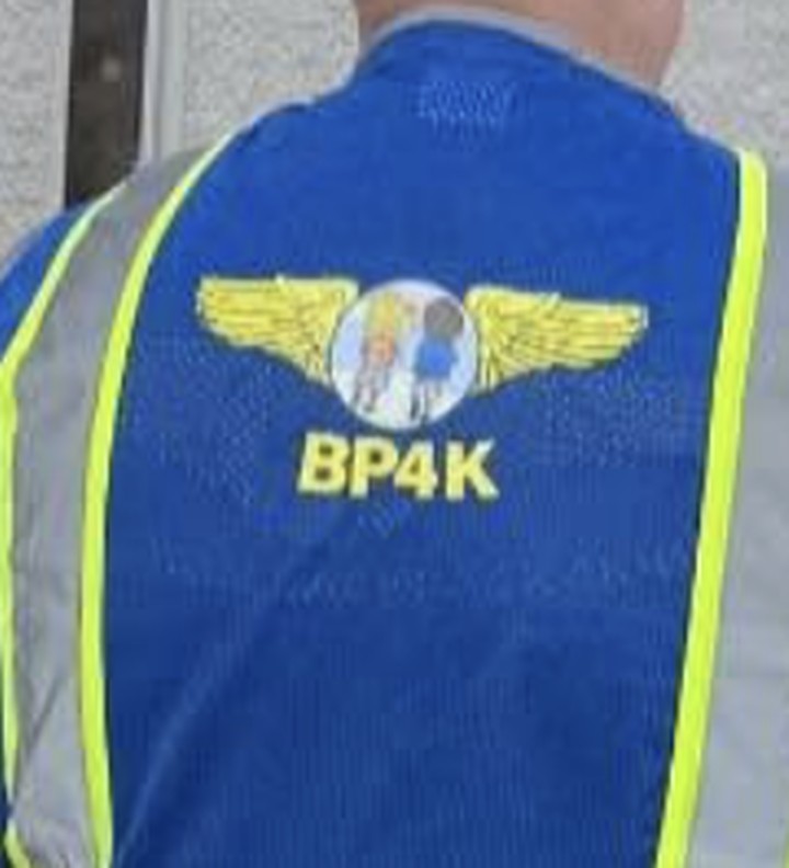 The back of a blue safety vest printed with golden wings and the letters BP4K