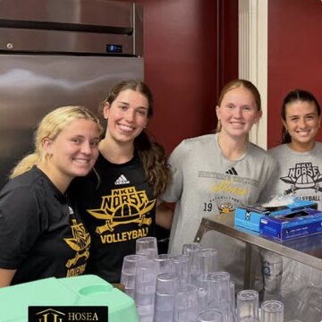 Members of a university volleyball team volunteering behind the Hosea House serving line