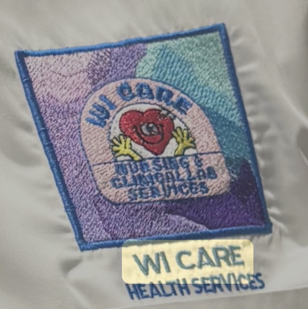An embroidered Wi Care Nursing and Clinical Lab Services patch showing a cartoon heart with raised hands
